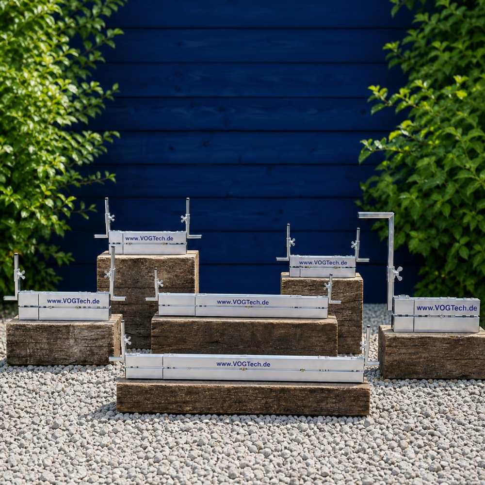 Abziehschienen alle Größen (H1 bis H5) auf Sockel platziert hinter einer blauen Holzfassade im Garten